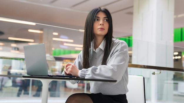 Uma jovem está trabalhando em um laptop em um café de shopping center