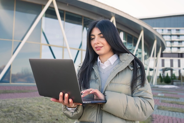 Uma jovem está trabalhando em um laptop na rua