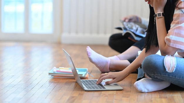 Uma jovem está usando um laptop que está colocando no chão da sala