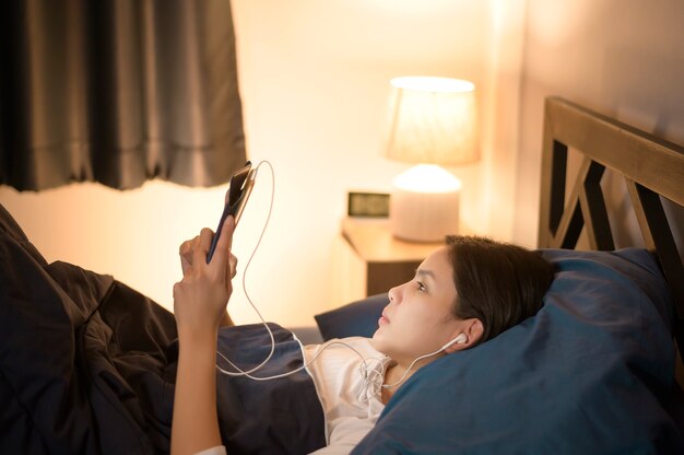 Uma jovem está usando um tablet, assistindo a filmes ou fazendo uma videochamada com amigos ou familiares em seu quarto, luz noturna