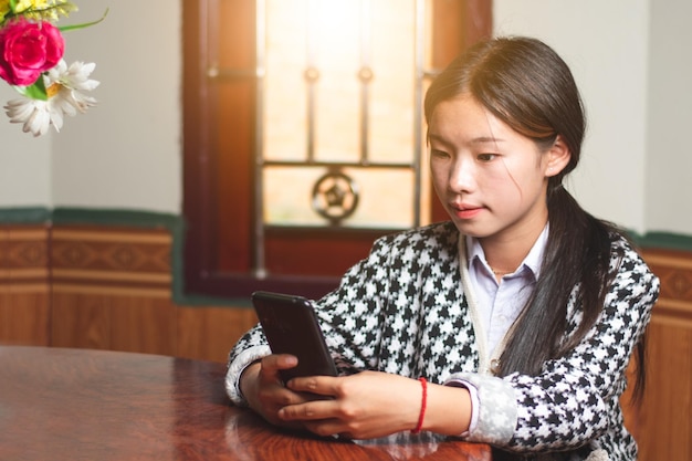 Uma jovem estudante bate-papo on-line com sua amiga nas mídias sociais do telefone celular e bate-papo conceito de conexão luz do sol através do espaço de cópia das janelas para texto individual