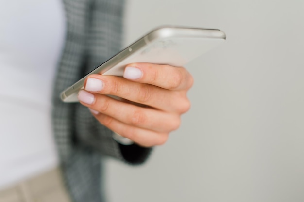 Uma jovem estudante sentada à mesa, usando smartpone ao estudar.