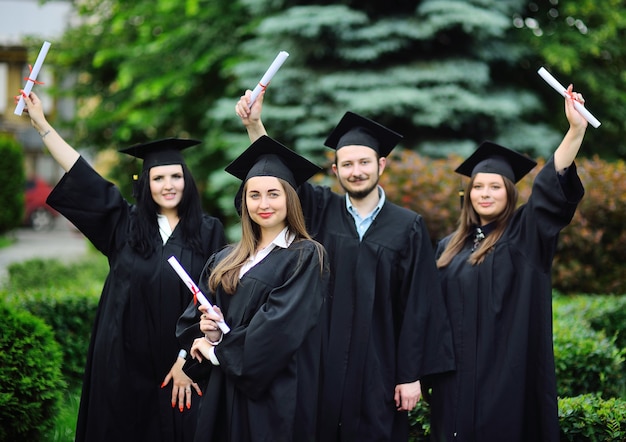 Uma jovem estudante universitária com uma túnica preta e um chapéu quadrado com um diploma na mão ...