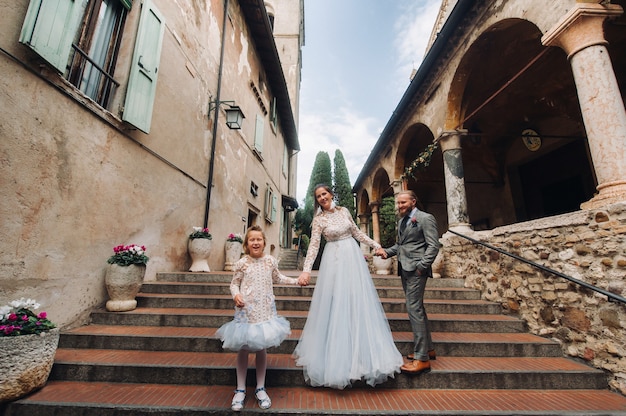 Uma jovem família feliz caminha pela cidade velha de Sirmione, na Itália. Família elegante na Itália em uma caminhada.