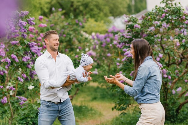 Uma jovem família feliz está se divertindo e caminhando em um parque de primavera em flor.