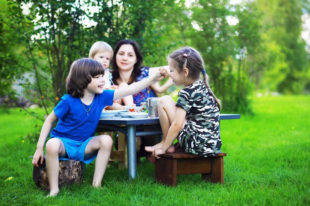 Uma jovem família grande em um piquenique em uma manhã de verãoMãe com filhos está tomando café da manhã no parque