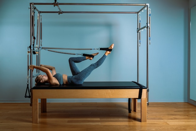 Uma jovem faz exercícios de Pilates com um reformador de cama