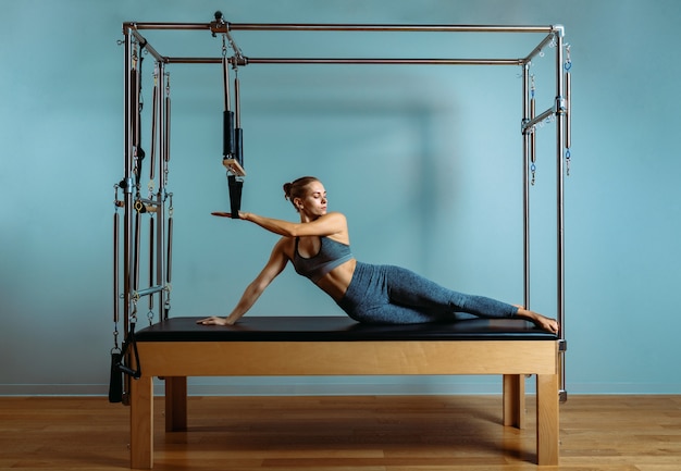 Uma jovem faz exercícios de pilates com um reformador de cama