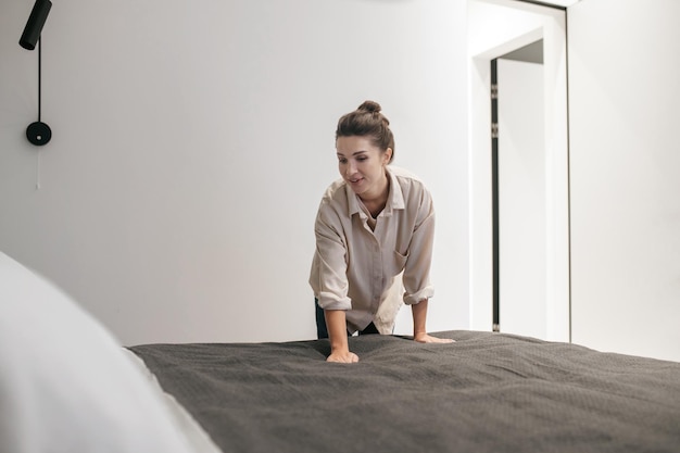 Uma jovem fazendo a cama e parecendo positiva