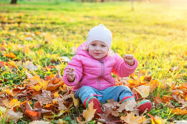 Uma jovem feliz brincando sob folhas amarelas caindo no belo parque de outono na natureza caminha ao ar livre