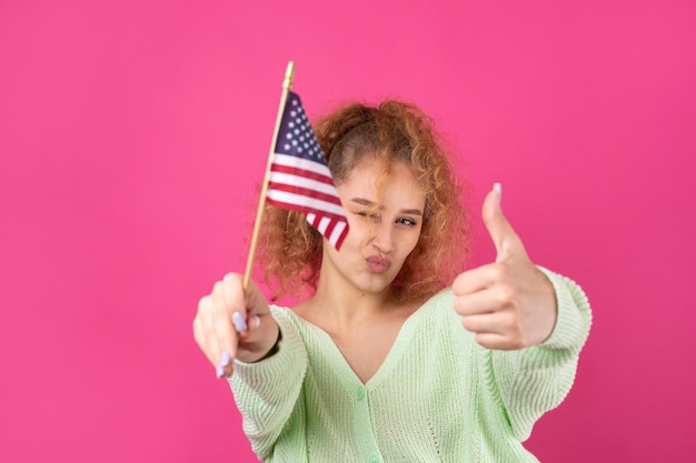 Foto uma jovem feliz com um sorriso no rosto segura uma bandeira americana em suas mãos símbolo de patriotismo e liberdade