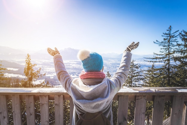 Uma jovem feliz está levantando as mãos na montanha apreciando a vista sobre Salzburgo, horário de inverno em Gaisberg Salzburg, Áustria