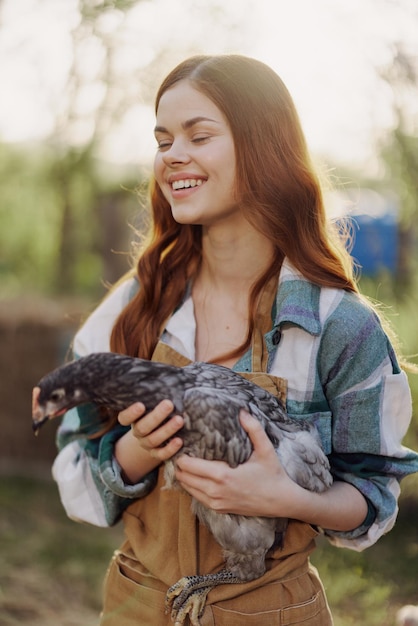 Uma jovem feliz sorrindo e segurando uma galinha jovem que põe ovos para sua fazenda