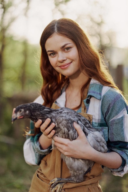 Uma jovem feliz sorrindo e segurando uma galinha jovem que põe ovos para sua fazenda