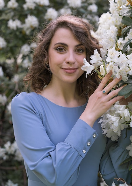 Uma jovem fica perto de flores brancas Frescura da juventude