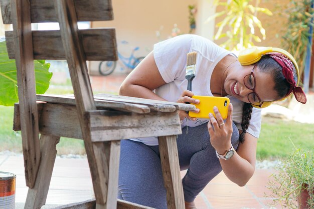 Uma jovem fotografa uma cadeira que está se preparando para pintar