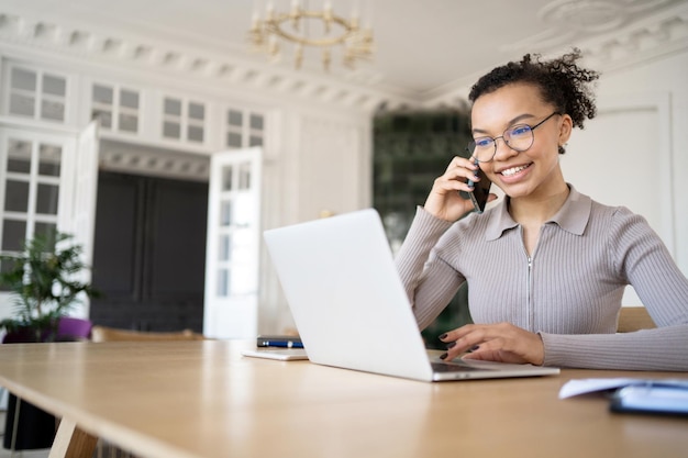 Uma jovem freelance está trabalhando no escritório em um novo projeto em uma empresa financeira usando um laptop na mesa