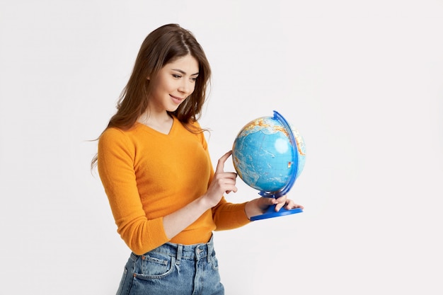 Uma jovem garota atraente escolhe um lugar para descansar em um grande globo. Férias, viagens