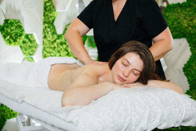 Uma jovem garota bonita está desfrutando de uma massagem cosmetológica profissional no spa. Cuidados com o corpo. Salão de beleza.
