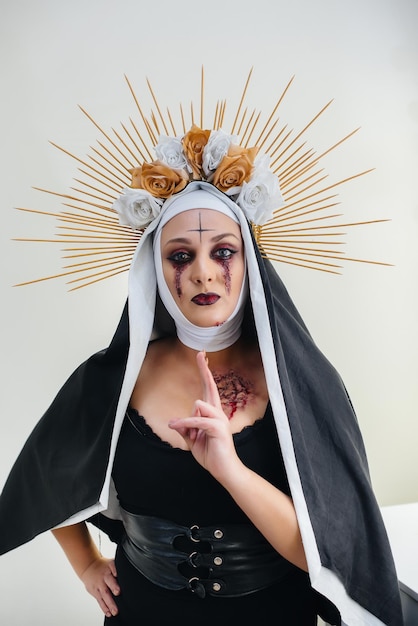 Uma jovem garota com uma bela maquiagem festiva e uma fantasia de freira assustadora para o feriado de Halloween. Conceito de feliz dia das bruxas.