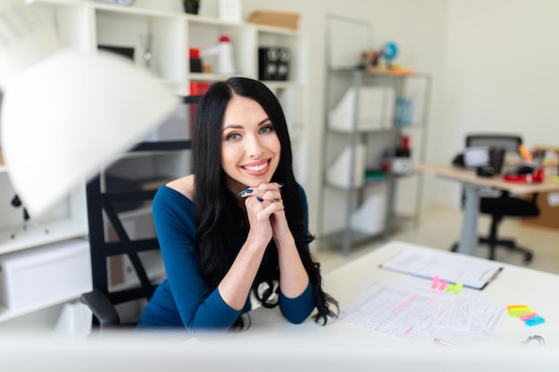 Uma jovem garota está sentada no escritório à mesa.