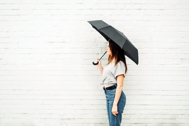 Uma jovem garota fica com um guarda-chuva preto