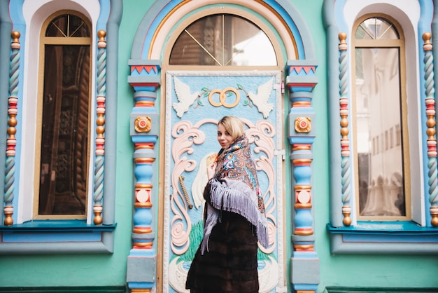 Uma jovem garota linda com um casaco de vison e um cachecol folclórico russo anda pelo kremlin de izmailovo. moscou, rússia.