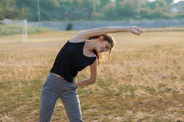 Uma jovem garota magra e atlética em roupas esportivas com estampas de pele de cobra realiza uma série de exercícios
