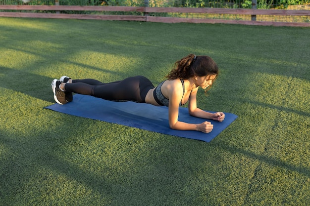 Foto uma jovem garota magra e atlética em roupas esportivas com estampas de pele de cobra realiza uma série de exercícios