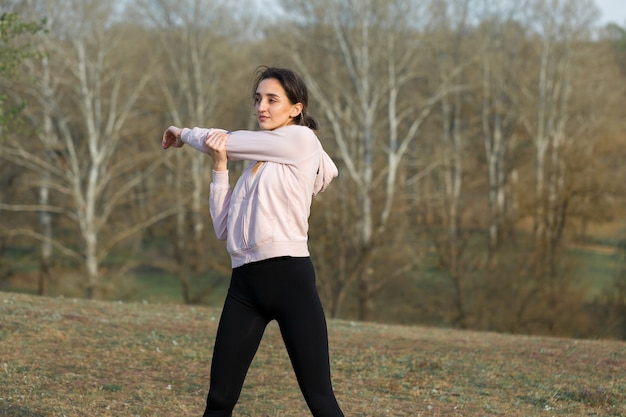 Uma jovem garota magra e atlética em roupas esportivas realiza uma série de exercícios fitness e estilo de vida saudável