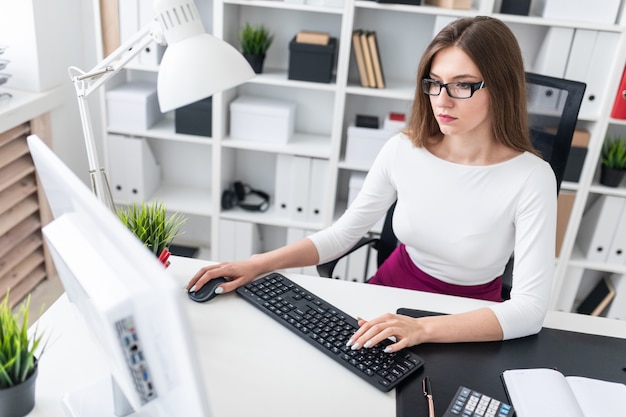 Uma jovem garota sentada em uma mesa e digitando no teclado.