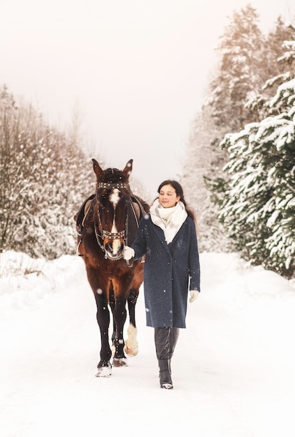 Uma jovem garota simática dá um passeio a cavalo no inverno na natureza. Amizade humano-animal