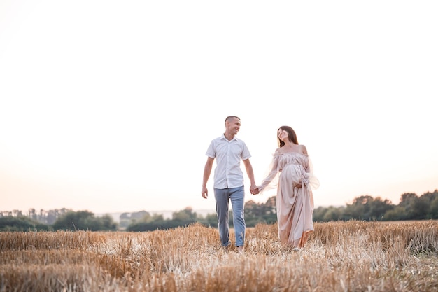 Uma jovem grávida com seu marido um lindo casal feliz abraçando em um campo dourado no campo Relações familiares Futuros pais