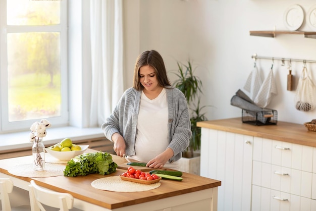 uma jovem grávida faz uma salada de legumes frescos o conceito de nutrição adequada