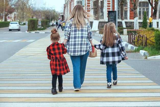 uma jovem guia duas meninas pela estrada em uma faixa de pedestres