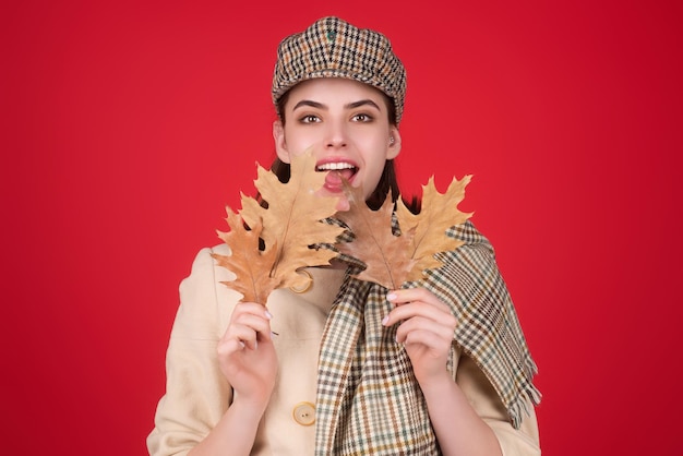 Uma jovem hipster com roupa de outono na moda, chapéu estiloso e cachecol, garota de beleza, segura licença de outono