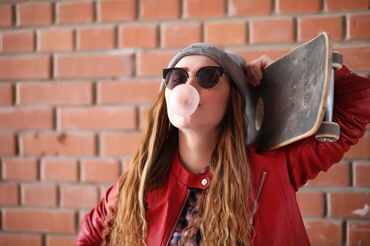 Foto uma jovem hipster está a andar de skate. amigas de raparigas a passear pela cidade com um skate. desportos de primavera na rua com um skate.