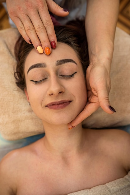 Uma jovem incrivelmente bonita com contornos faciais perfeitos faz uma massagem facial rejuvenescedora