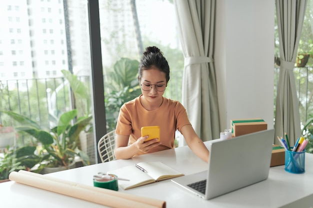 Uma jovem iniciando um negócio online trabalha em seu laptop e espera por pedidos