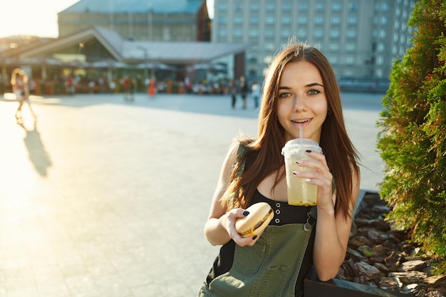 Uma jovem janta fast food na praça da cidade