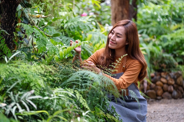 Uma jovem jardineira asiática cuidando de plantas no jardim