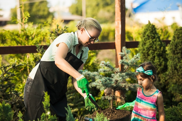 Uma jovem jardineira mostra uma menina transplantando uma planta em solo fértil