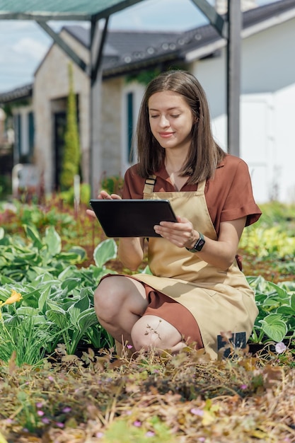 Uma jovem jardineira segura um gadget e verifica informações sobre plantas em um centro de jardinagem