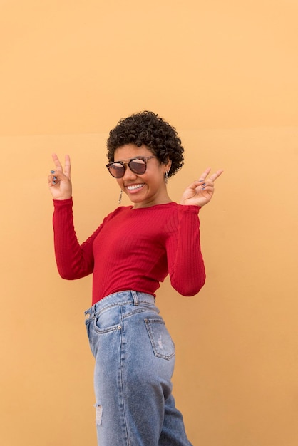 Uma jovem latina posando e sorrindo em frente a parede laranja com óculos de sol Panamá