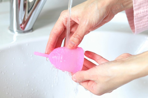 Uma jovem lava um copo menstrual no banheiro