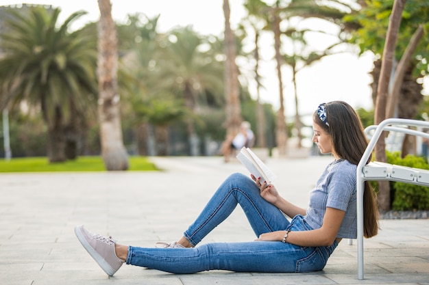 Uma jovem lendo um livro na rua