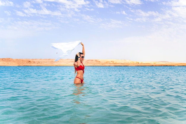 Uma jovem linda caminha sobre a água turquesa do mar vermelho Sharm el Sheikh Egito O conceito de férias de verão à beira-mar