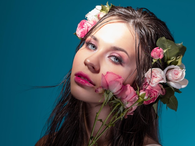 Uma jovem linda com flores rosas em seu cabelo molhado retrato de uma linda morena com perf...