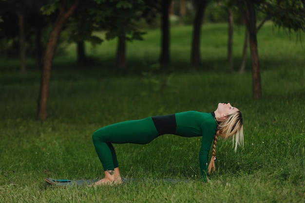 Uma jovem linda está fazendo ioga em uma noite calma e quente na grama