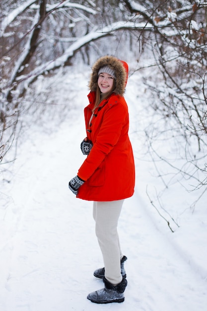 Uma jovem, loira, com um suéter, um chapéu e uma jaqueta laranja, tendo como pano de fundo a paisagem de inverno. neve e geada, o conceito de natal.